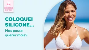 É possível aumentar o silicone? Descubra como é feita a troca de próteses para conquistar o volume dos seus sonhos Imagem mostrando uma mulher sorrindo na praia, usando um biquíni na cor branca