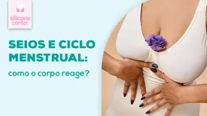 Ciclo menstrual: como ele afeta o tamanho dos seios? Imagem mostrando o corpo de uma mulher, com uma flor de cor roxa no meio do decote, com as mãos sobre a barriga