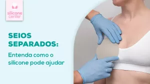 Seios separados: como corrigir? Imagem mostrando uma mulher usando um sutiã branco, com uma pessoa segurando uma prótese de silicone na frente de um dos seios
