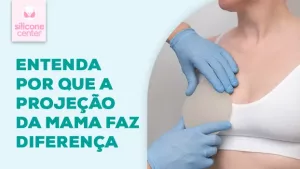 Imagem mostrando o tronco de uma mulher, onde ela está usanod um top branco, e tem uma mão com luvas colocando uma prótese de silicone na frente de uma dos seios da mulher